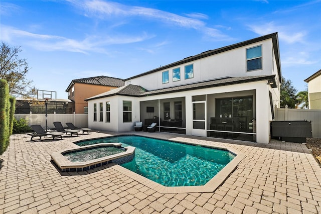 rear view of property with a swimming pool with hot tub, a patio area, and a sunroom