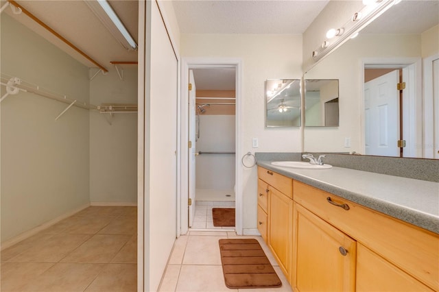 bathroom with a shower, a textured ceiling, vanity, and tile patterned floors