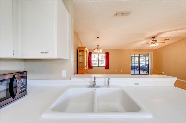 kitchen featuring kitchen peninsula, ceiling fan, sink, decorative light fixtures, and white cabinetry