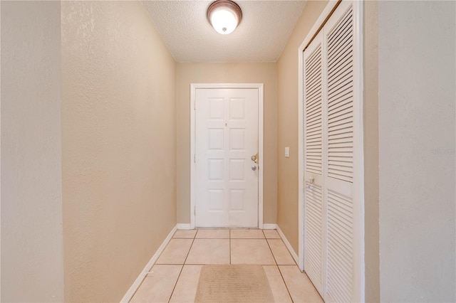 hallway with light tile patterned floors and a textured ceiling