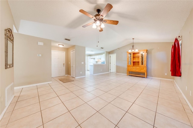 spare room with light tile patterned floors, ceiling fan with notable chandelier, a textured ceiling, and vaulted ceiling