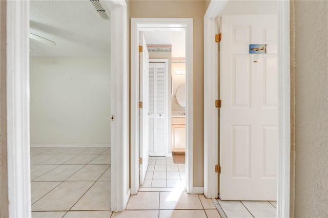 hall with light tile patterned flooring and a textured ceiling