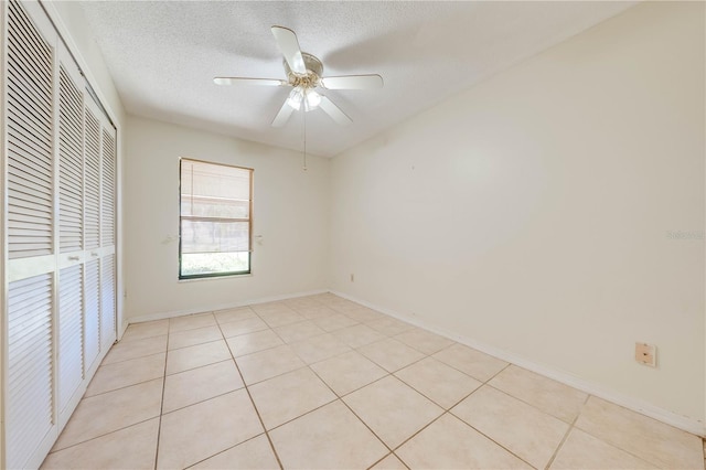 unfurnished bedroom featuring ceiling fan, light tile patterned floors, a textured ceiling, and a closet