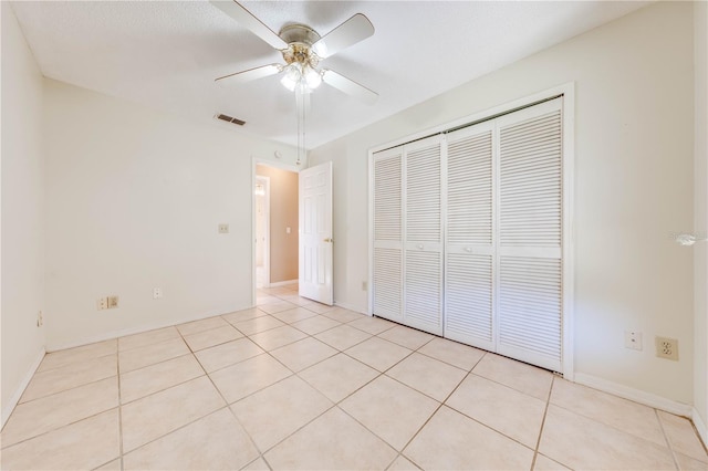 unfurnished bedroom with ceiling fan, light tile patterned floors, a textured ceiling, and a closet