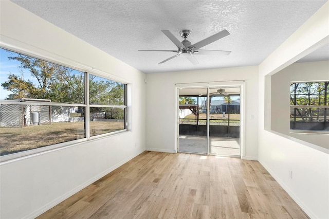 spare room with a healthy amount of sunlight, light hardwood / wood-style floors, and a textured ceiling