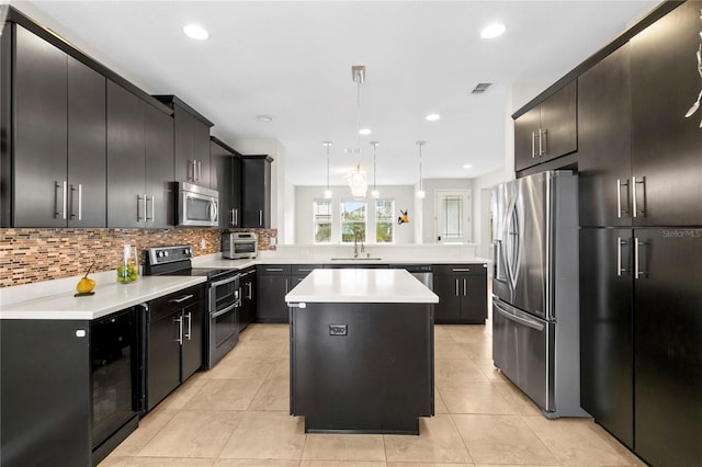 kitchen with decorative backsplash, appliances with stainless steel finishes, beverage cooler, decorative light fixtures, and a center island