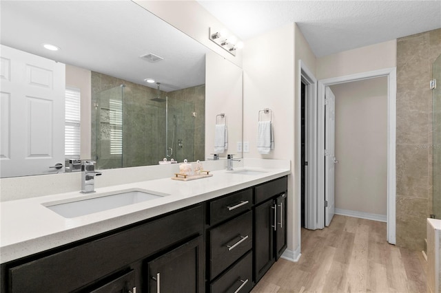 bathroom with hardwood / wood-style floors, vanity, a shower with door, and a textured ceiling