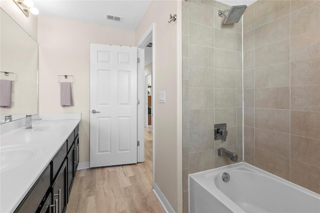 bathroom with vanity, hardwood / wood-style flooring, and tiled shower / bath