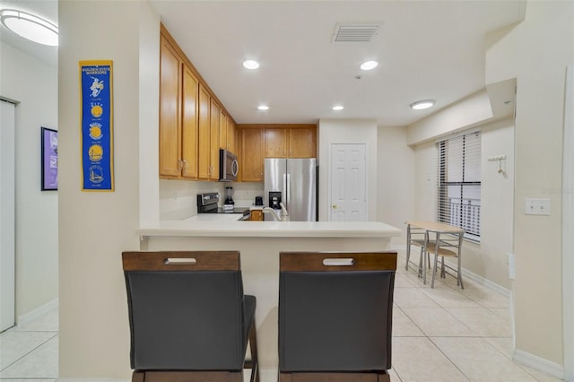 kitchen featuring kitchen peninsula, light tile patterned floors, and stainless steel appliances