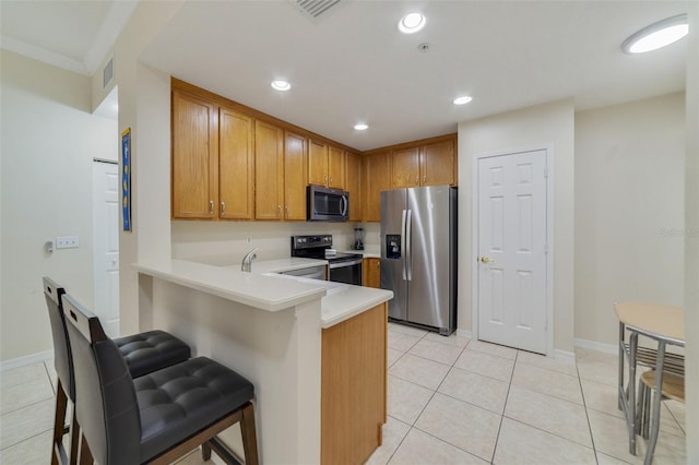 kitchen with a kitchen bar, kitchen peninsula, light tile patterned floors, and appliances with stainless steel finishes