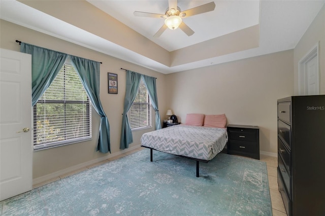 bedroom featuring ceiling fan, light tile patterned floors, and a tray ceiling