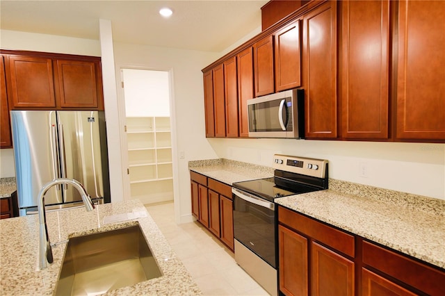 kitchen featuring light stone counters, sink, and stainless steel appliances