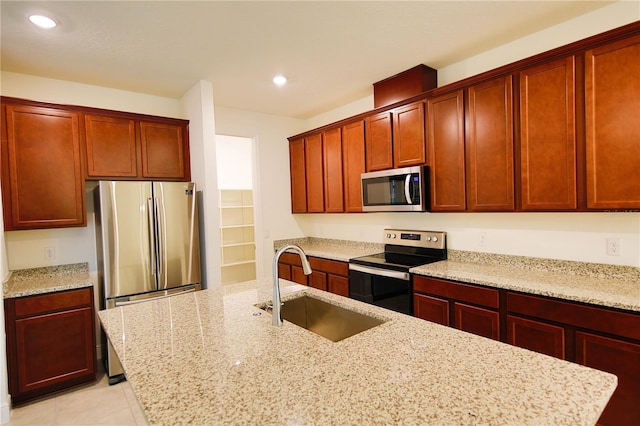 kitchen with light tile patterned flooring, appliances with stainless steel finishes, light stone countertops, and sink