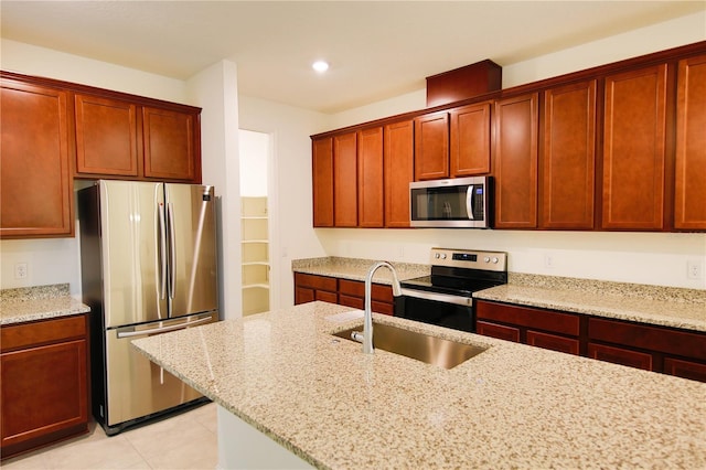 kitchen featuring light stone counters, sink, light tile patterned floors, and stainless steel appliances