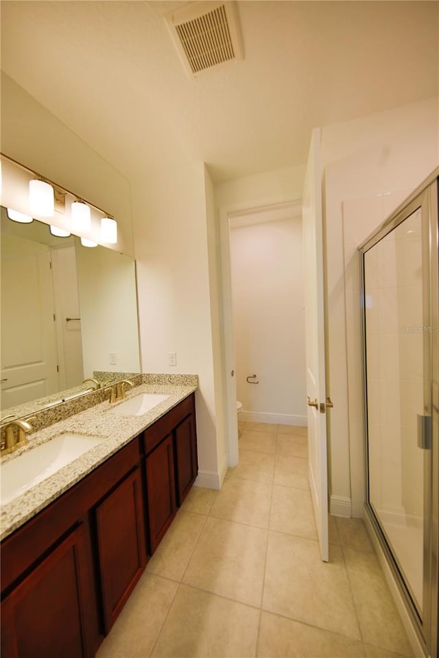 bathroom with tile patterned floors, toilet, a shower with shower door, and vanity