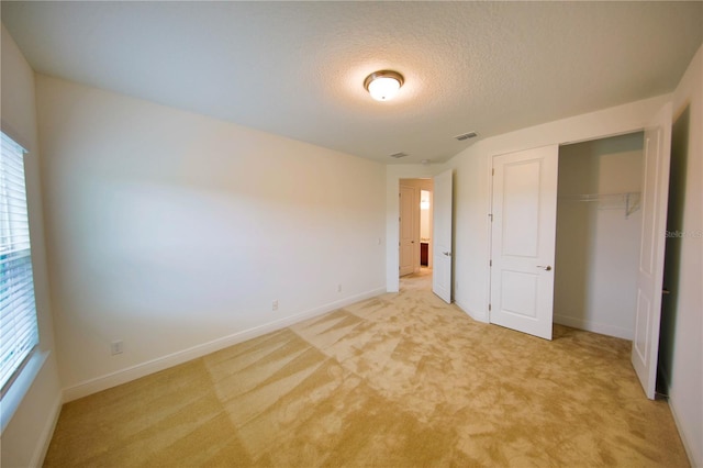 unfurnished bedroom with light colored carpet, a closet, and a textured ceiling