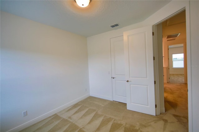 unfurnished bedroom featuring light colored carpet and a textured ceiling