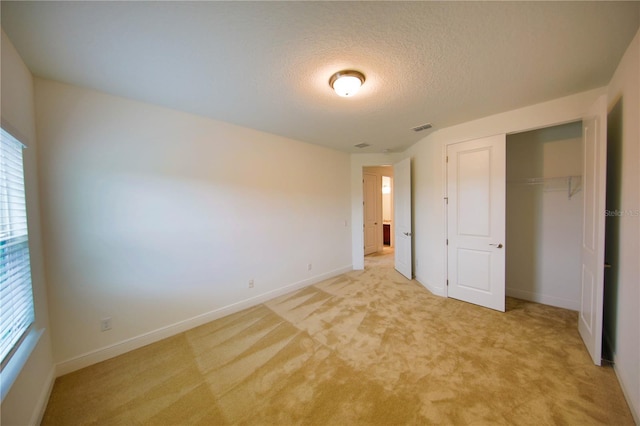 unfurnished bedroom featuring light carpet, a closet, and a textured ceiling