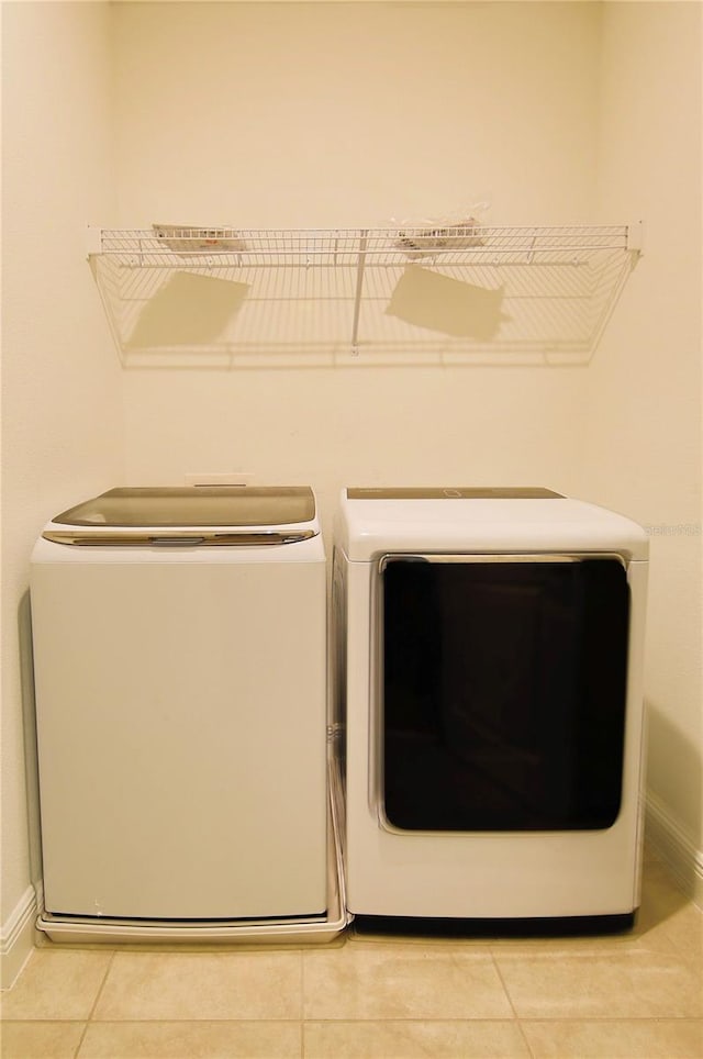 clothes washing area with light tile patterned flooring and washing machine and clothes dryer