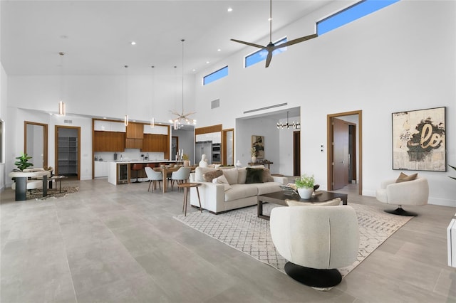 living room featuring ceiling fan with notable chandelier and a high ceiling