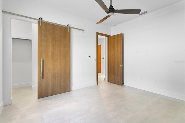 unfurnished bedroom with ceiling fan, a closet, and a barn door