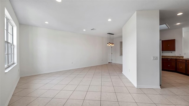 empty room with a chandelier and light tile patterned floors