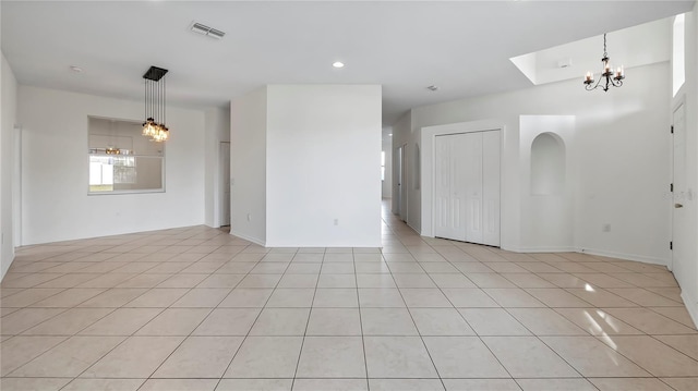 tiled empty room with a notable chandelier