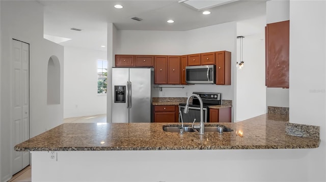 kitchen with sink, light tile patterned floors, stainless steel appliances, kitchen peninsula, and dark stone counters