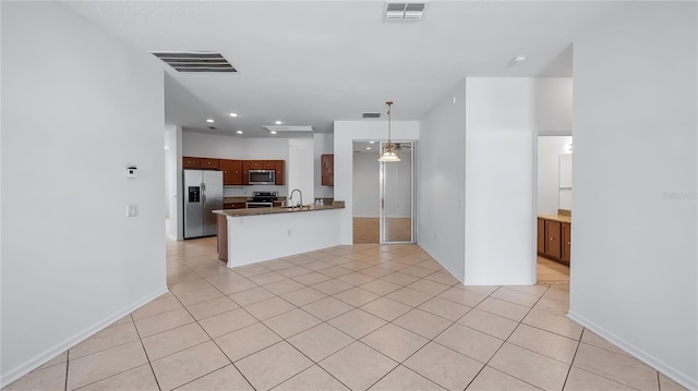 kitchen with light tile patterned floors, stainless steel appliances, and kitchen peninsula