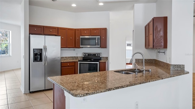 kitchen with appliances with stainless steel finishes, sink, dark stone countertops, and kitchen peninsula