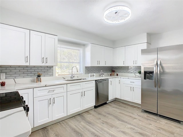 kitchen with sink, appliances with stainless steel finishes, backsplash, light hardwood / wood-style floors, and white cabinets