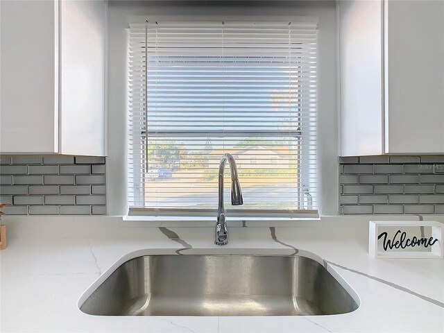 details with white cabinetry, sink, and backsplash