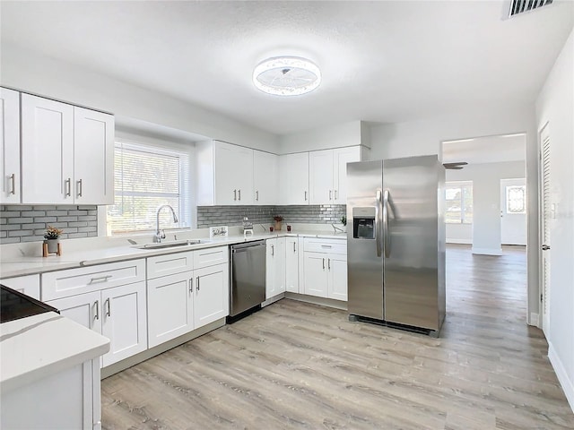 kitchen featuring white cabinetry, sink, light hardwood / wood-style flooring, and appliances with stainless steel finishes