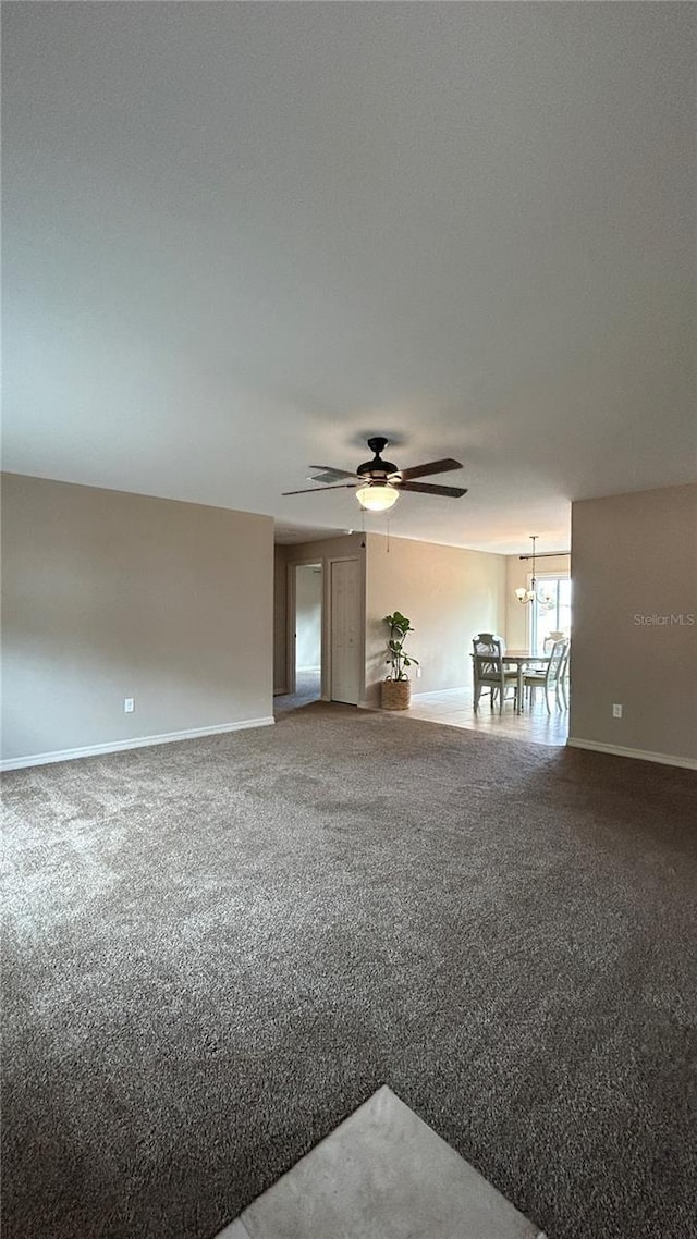 carpeted spare room featuring ceiling fan with notable chandelier