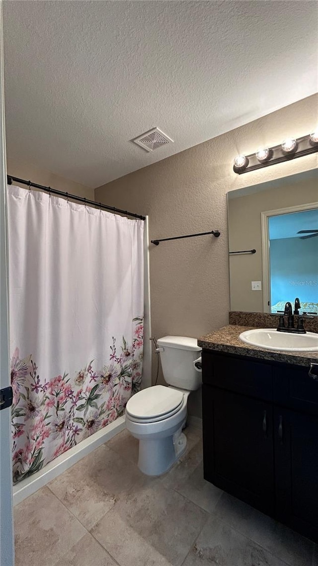 bathroom featuring vanity, a textured ceiling, and toilet