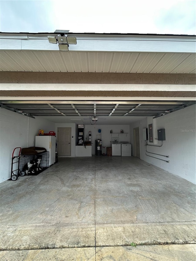 garage with washing machine and dryer, water heater, electric panel, and white fridge