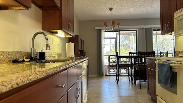 kitchen featuring light stone countertops, sink, an inviting chandelier, decorative light fixtures, and light tile patterned floors