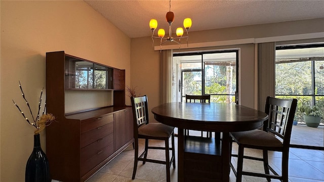 dining area with light tile patterned floors, a textured ceiling, and an inviting chandelier