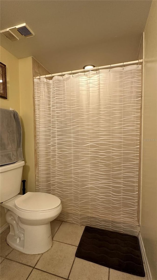 bathroom featuring tile patterned flooring, toilet, and walk in shower