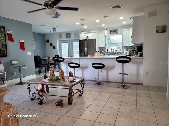 kitchen with white cabinets, hanging light fixtures, ceiling fan, appliances with stainless steel finishes, and a kitchen bar