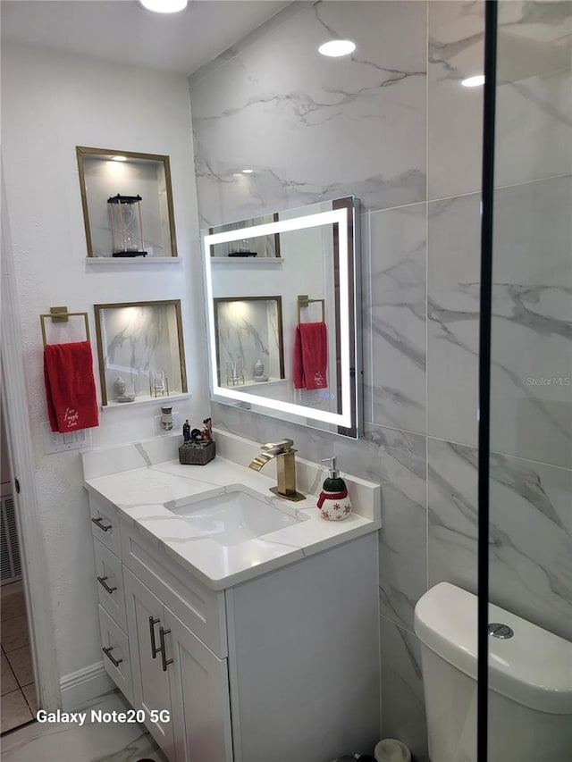 bathroom with vanity, toilet, and tile walls