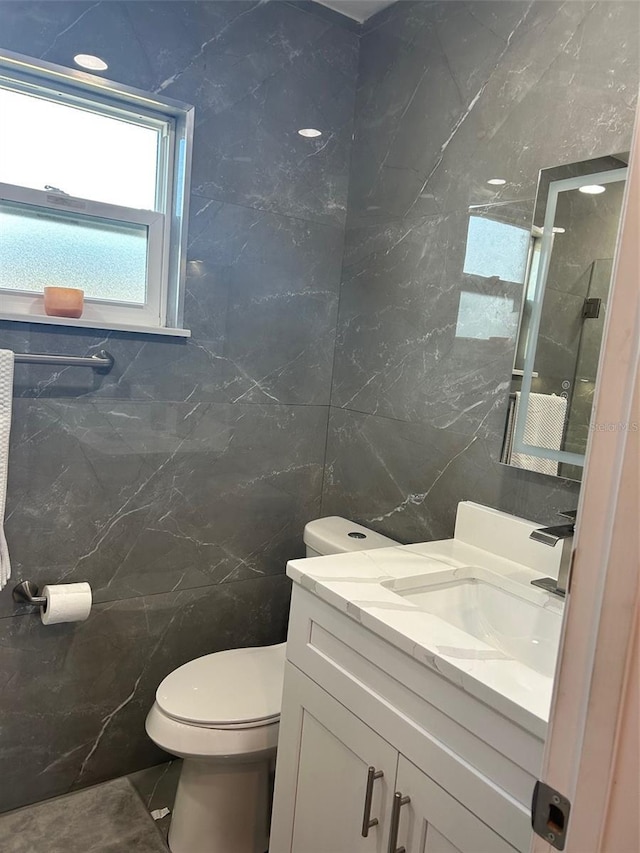 bathroom with vanity, tile walls, and toilet