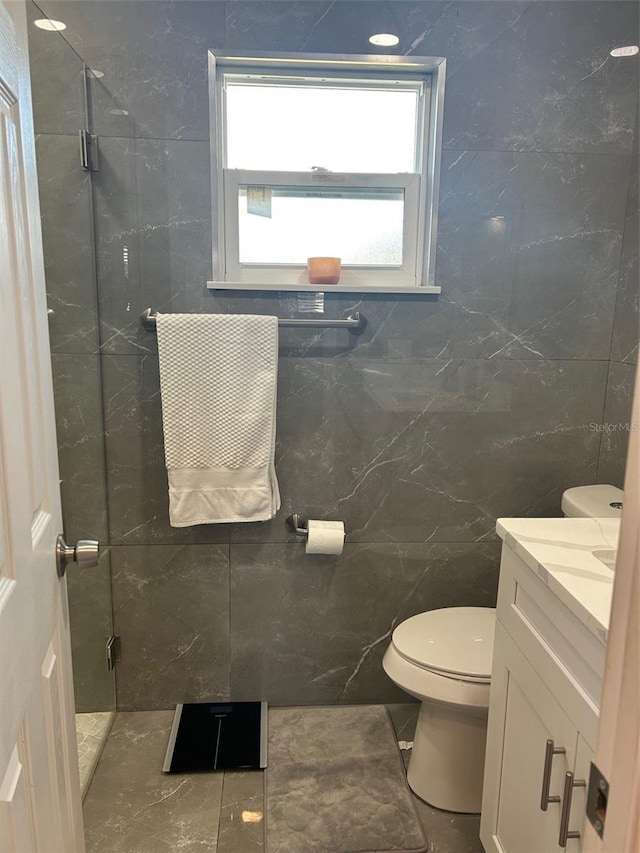 bathroom featuring walk in shower, vanity, tile patterned floors, and tile walls