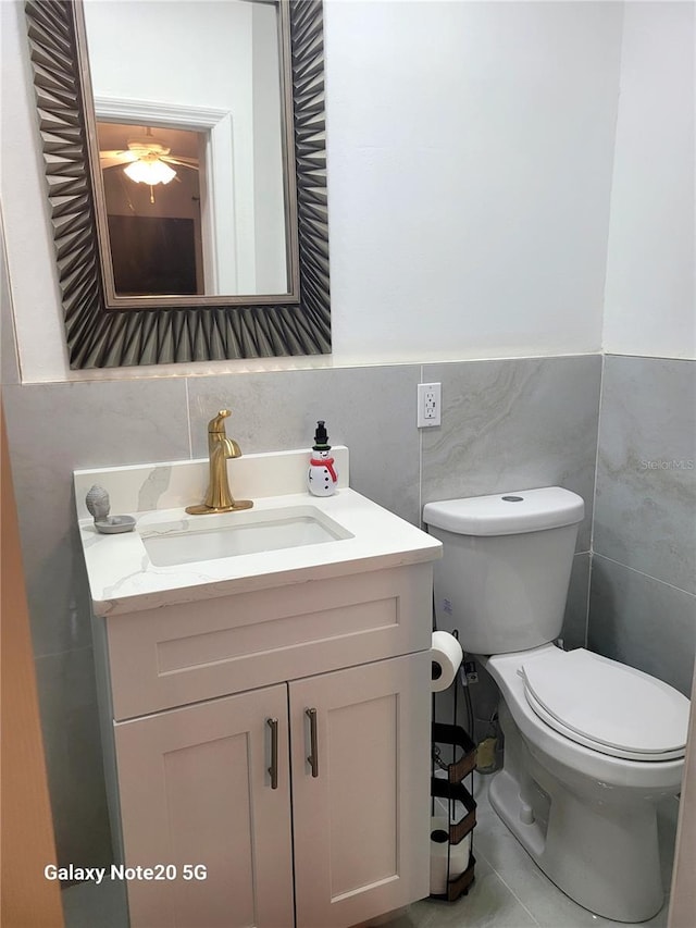 bathroom with tile patterned floors, vanity, toilet, and tile walls