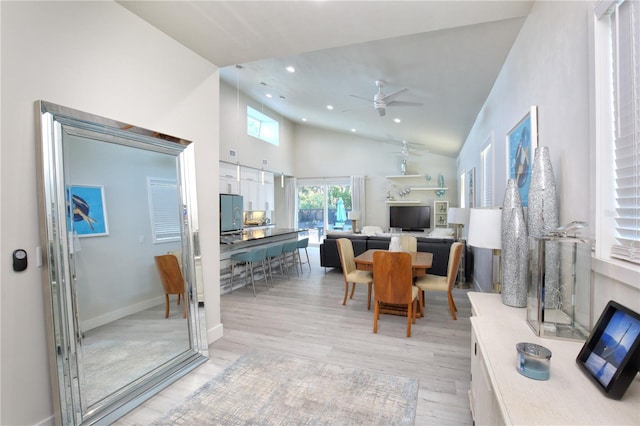 dining room featuring light wood-type flooring, high vaulted ceiling, and ceiling fan