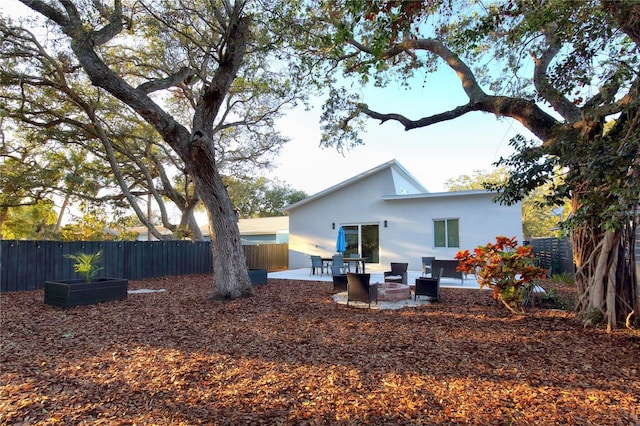 rear view of property featuring a patio area and an outdoor fire pit