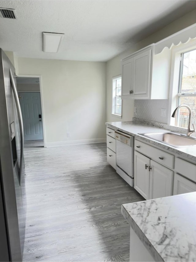 kitchen featuring a wealth of natural light, dishwasher, white cabinets, and sink