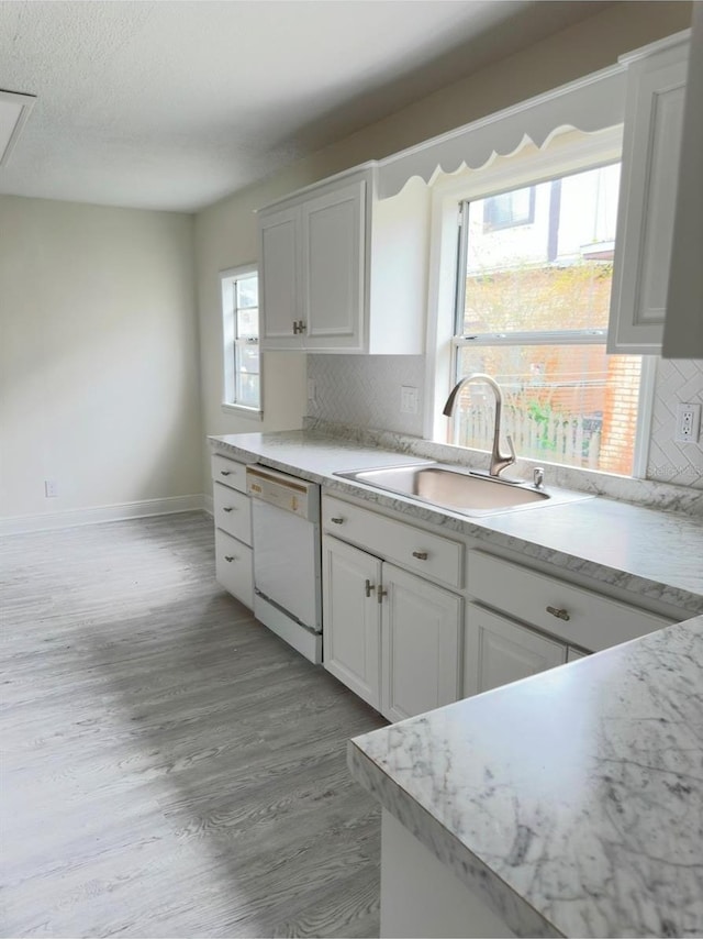 kitchen with dishwasher, backsplash, sink, light hardwood / wood-style floors, and white cabinetry