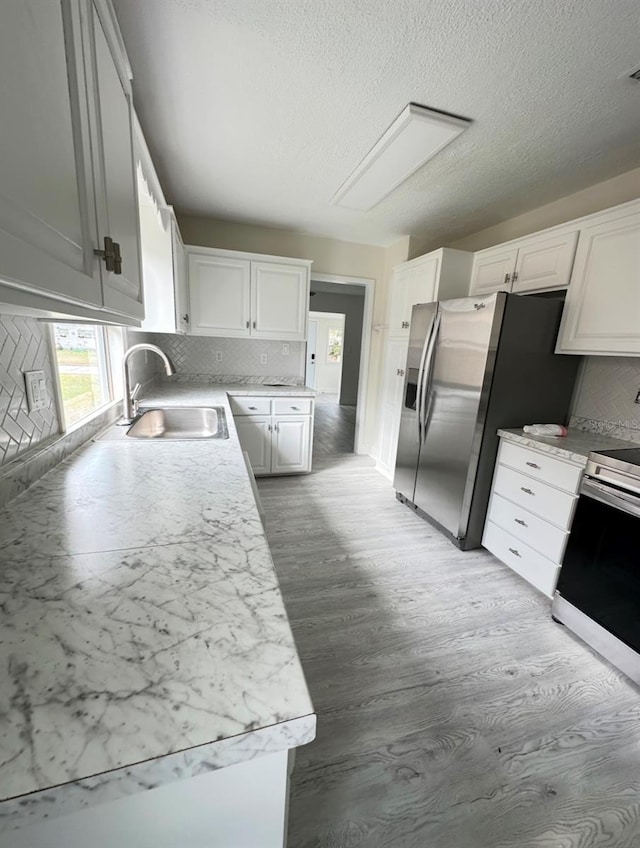 kitchen with hardwood / wood-style floors, sink, stainless steel fridge, range with electric stovetop, and white cabinetry