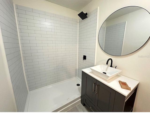 bathroom with vanity, a textured ceiling, and tiled shower